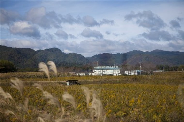 A deserted field and buildings inside the contaminated exclusion zone around the crippled Fukushima Dai-ichi nuclear power station are seen through a bus window near Okuma, Japan Saturday, Nov. 12, 2011. (AP Photo/David Guttenfelder, Pool)